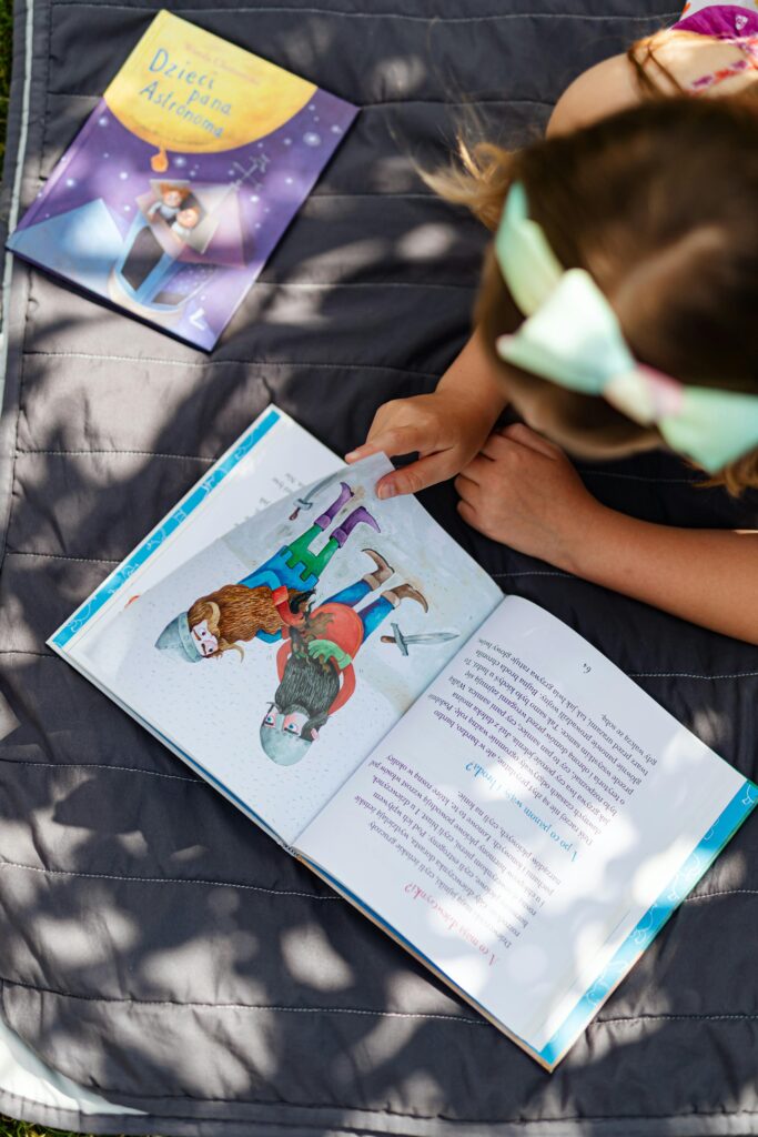 絵本を読む6歳～8歳くらいのリボンのヘアバンドをつけた女の子の写真