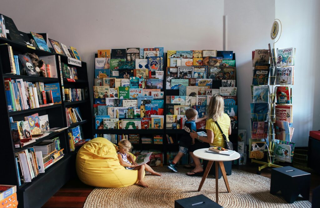 絵本が本棚にたくさんある部屋で男の子と女の子、大人がいる写真