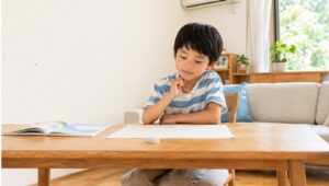 絵本を読み終えたあと、リビングテーブルで原稿用紙を前に考えている小学校低学年くらいの男の子の様子